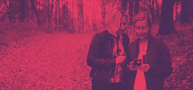 Telia and RISE granted funding for 5G networks. Two women looking at cell phone in forest